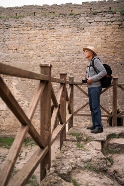 Yaşlı erkek turist antik kaleyi geziyor ve uzaklığa bakıyor. Boşluğu kopyala