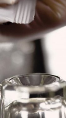 Kaş boyama. Bir güzellik uzmanı cam bir kabın içine kaş boyası sıkıyor, yakın plan. Dikey video