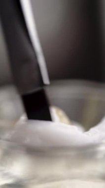 Kaş boyası. Güzellik uzmanlarının ellerinin boyayla oksitleyiciyi birbirine karıştırıp yüzünü boyamak için fırçayla taradığı yakın plan. Boşluğu kopyala