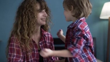 Oğlu annesini öpüyor. Anne ve çocuk oturma odasında sarılıyor. Anneler Günün kutlu olsun. Çocuk sevgiyle annesini öpüyor. Boşluğu kopyala