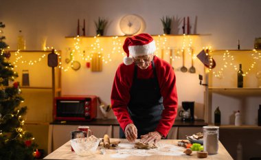 Noel Baba şapkalı yaşlı adam Noel boyunca mutfak tezgahında hamur yoğurur. Kurabiye kesiciler, oklavalar ve Noel ışıklarıyla çevrili halde zencefilli kurabiye pişirir ve bayramı yakalar.
