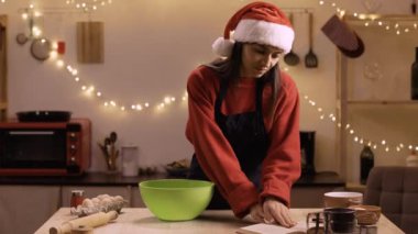 Mutfakta yemek tarifi kitabı okuyan Latin bir kadın Noel arifesinde yemek hazırlıyor. Noel gelenekleri kavramı