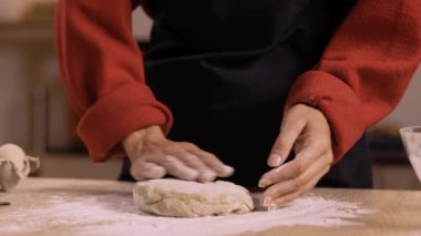 Zencefilli kurabiye için hamuru un yüzeyinde yoğuran kadın ellerine yakın plan. Noel pişirme sürecinde mutfak ortamında hamuru hazırlamaya odaklan.