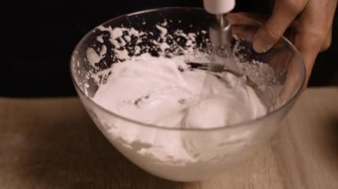 Pişirme konsepti. Şef kremalı pasta pişiriyor, yakın plan. Karıştırıcı çırpıcısında çırpılmış yumurta beyazı. Boşluğu kopyala