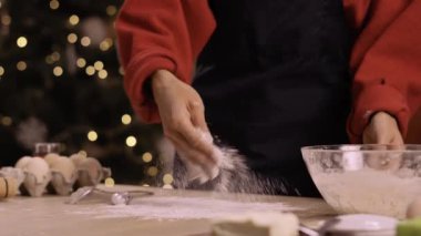 Geleneksel Noel kurabiyeleri için hamur toplarken, bir yandan da un döken bir kadın. Kış tatili konsepti. Yakın plan.