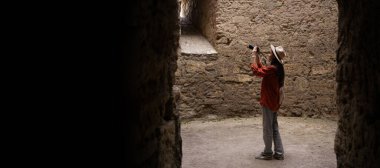 Kadın turist eski bir kaleyi keşfediyor, kamerasıyla fotoğraf çekiyor. Kalenin içinde, tarihi detayları yakalıyor ve seyahati boyunca gezinin tadını çıkarıyor..