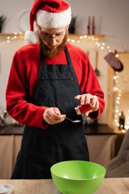 Önlüklü mutlu adam evde mutfakta yemek pişirirken kış tatilinde hamura baharat dökerken Noel kurabiyesi yapıyor. Boşluğu kopyala