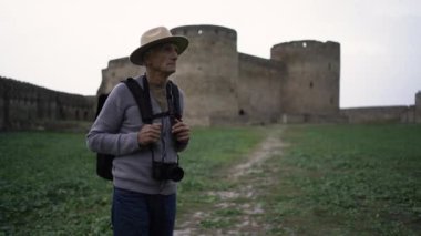 Emekli turist, antik kalede boynunda kamerayla eski kasabayı gezerken görülüyor. Seyahat ve turizm kavramı