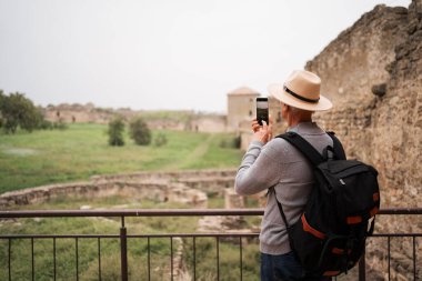Emekli adam gezip geziyor ve cep telefonuyla fotoğraf çekiyor. Yan görünüm