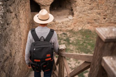 Sırt çantalı bir turist eski kalenin merdivenlerinden aşağı iniyor. Seyahat ve turizm kavramı