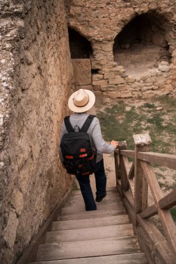 Sırt çantalı bir turist eski kalenin merdivenlerinden aşağı iniyor. Seyahat ve turizm kavramı