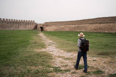 Eski kale manzarasında yürüyen mutlu yaşlı bir adam. Emekli insan ilkbaharda gezintiden zevk alıyor. Emeklilerin tatilleri. Boşluğu kopyala