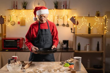 Emekli adam Noel arifesinde sıcak mutfakta zencefilli kurabiye pişiriyor. Noel Baba şapkası ve önlüğü takarak etrafı pişirme aletleri ve dekorasyonlarla çevrili ziyafetler hazırlıyor..