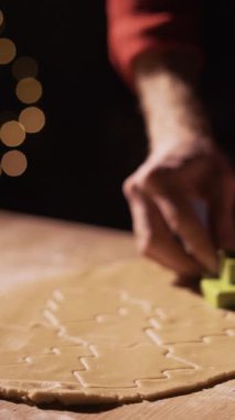 Adam hamurdan zencefilli kurabiye pişiriyor ve zencefilli kek ağaçlarına kesiyor. Yakın plan.