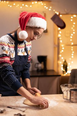 Evde Noel için zencefilli ekmek yapmak için hamur hazırlayan kadın portresi. Ev hanımı tatil için arkadaşlarına pasta yapıyor.