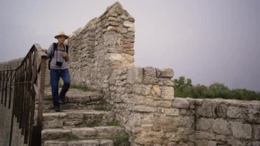 Emekli turist, antik kalede boynunda kamerayla eski kasabayı gezerken görülüyor. Boşluğu kopyala