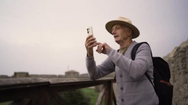 Emekli adam, sosyal ağdaki haberleri için akıllı telefondan fotoğraf çekiyor. Yaşam tarzı olarak seyahat etmek. Boşluğu kopyala