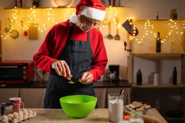 Son sınıf öğrencisi Noel için evde mutfakta zencefilli ekmek yapmak için hamur hazırlıyor. Önlüklü Büyükbaba Pasta Yapıyor. Boşluğu kopyala