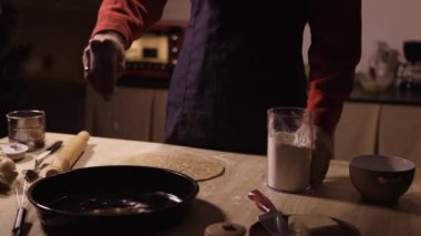 Noel kurabiyeleri ve çatal bıçaklarla çevrili bir tepsiye un döken tanınmamış bir adam. Boşluğu kopyala