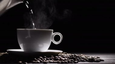 Siyah arka planda hazır kahveyle beyaz bardağa sıcak su dökmek. Boşluğu kopyala