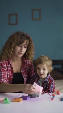 Anne ve oğlu renkli modelleme kil ile eğlenceli bir aktivite içinde, şekiller ve figürler oluşturdular. Anne çocuğuna rehberlik eder, yaratıcılığı ve bağlanma süresini arttırır..