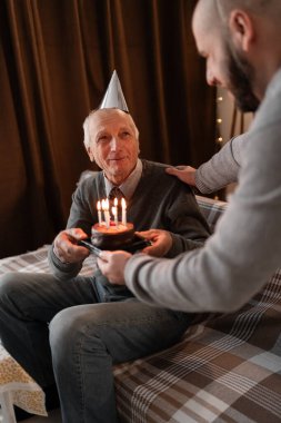 Mutlu yaşlı baba ve bin yıllık oğul doğum gününü kutluyor, genç adam yıldönümlerinde mumlu yaşlı adam pastası getiriyor. Boşluğu kopyala