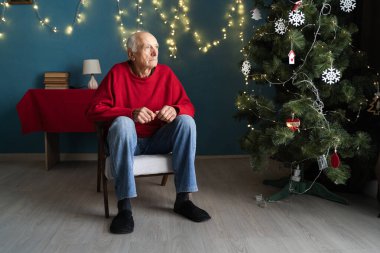 lonely pensioner sitting on a chair in the living room at Christmas expecting children. Copy space clipart