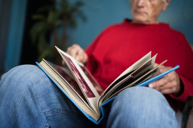 Elinde fotoğraf albümleri olan dul bir adam ve ölmüş karısını hatırlıyor. Yakın plan. Geniş açı
