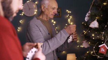 Adam, Noel zamanı yaşlı babanın evde ağaç süslemesine yardım ediyor. Aile iki adam Noel 'i kutlamaya hazırlanıyor. Boşluğu kopyala