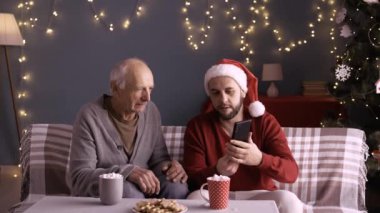 Erkekler, aileler, yaşlı babalar ve yetişkin çocuklar sosyal medya için akıllı telefon kullanmaktan zevk alıyorlar. Noel 'de koltukta oturup, uzay kopyalayarak eğleniyorlar.