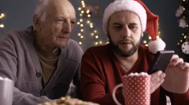 Oğlu, Baba 'ya Noel sabahı evde otururken akıllı telefonu nasıl kullanacağını öğretiyor. Boşluğu kopyala