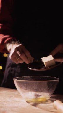 Hamur hazırlama süreci. Erkek fırıncı, Noel arifesinde karanlık arka planda kurabiye pişirmek için karıştırma kabına tereyağı ekler. Ev yapımı hamur işi tarifi. Boşluğu kopyala