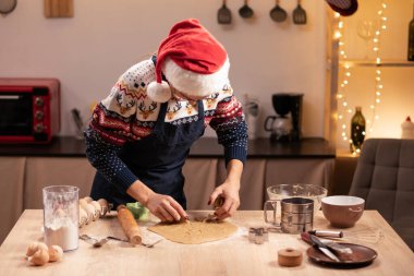 Noel ağacının yanındaki kırsal masada kesicilerle zencefilli kurabiye yapan bir kadın. Boşluğu kopyala