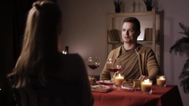 Sevgililer Günü 'nü evde yemek yiyip şarap içerek romantik bir akşam yemeği yiyen mutlu genç çift. Boşluğu kopyala