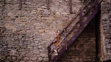 Yaşlı kalede yürüyen genç bir kadın yavaşça inen ahşap merdivenlerde. Boşluğu kopyala