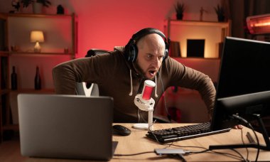 Ciddi bir adam online bilgisayar oyunu oynuyor, evde canlı yayın yapıyor, şüpheci ve alaycı görünüyor, ağzı açık kalınca şaşırıyor. Oyuncu yaşam tarzı ve teknoloji konsepti