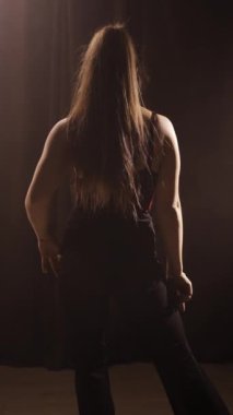 Karanlık bir odada dans eden bir kadın bazı dans figürleri sergiliyor. Yakın plan.