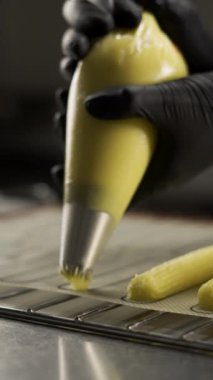 Eclair üretiminin süreci. Hamur torbasıyla hamur işi. Eklemeler. Pasta şefi pastacıda pasta yapıyor. Adım adım. Dikey video