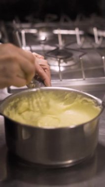 Kekler için krema pişirme sürecinde profiterol yapımında aşama aşama puding karıştırmak. Dikey video