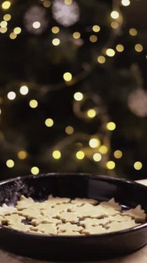 Noel arifesinde erkek eli servis tepsisiyle mutfakta çiğ zencefilli kurabiye. Dikey video