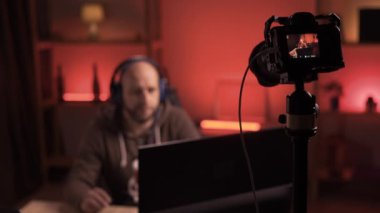 Oyun blogcusu evde video oyunu oynarken video blogu çekiyor. Genç siber sporcu oyunlarını online turnuvada oynuyor. Kameraya seçici odaklanma. Boşluğu kopyala