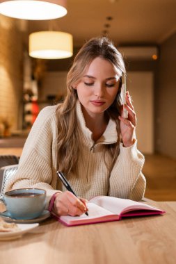 Bayan, kafede müşterilerle konuşurken notlar alıyor. Boşluğu kopyala