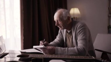 Son sınıf besteci adam evdeki oturma odasındaki koltukta gitar kullanarak beste yapıyor. Boşluğu kopyala