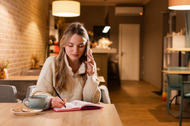 Bayan, kafede müşterilerle konuşurken notlar alıyor. Boşluğu kopyala