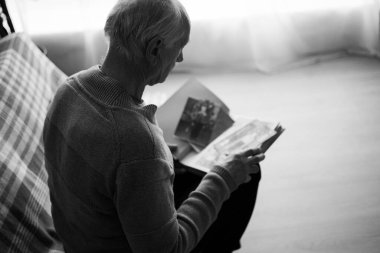 Eski fotoğraflara bakan üzgün kıdemli adam. Yalnızlık ve emeklilik bunalımı. Nostalji, hafıza ve konsepti unutma. Siyah beyaz fotoğraf