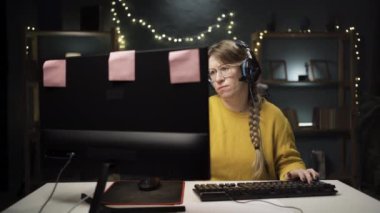 Gözlüklü yetişkin kadın oyuncu kişisel bilgisayarda online video oyununda bir tur oynuyor. Profesyonel oyuncu çoklu oyunculu çevrimiçi şampiyonanın tadını çıkartıyor. Elindeki görevi dikkatlice düşünüyor.