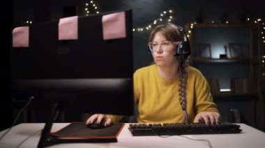 Gözlüklü yetişkin kadın oyuncu kişisel bilgisayarında online video oyununda bir tur oynuyor. Profesyonel oyuncu şampiyonluk çantalarının keyfini çıkarırken dudakları yüzünde hayal kırıklığını gösteriyor. Kavram kaybedildi