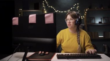 Gözlüklü yetişkin kadın oyuncu kişisel bilgisayarda online video oyununda bir tur oynuyor. Profesyonel oyuncunun şampiyonluktan hoşlanması onay jestini onaylıyor