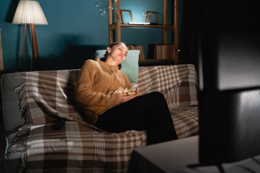 Genç esmer kadın geceleri kanepede televizyon izlerken uyuyakalıyor. Boşluğu kopyala