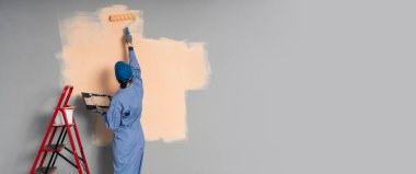 Arkadan bak. Boyacı mavi duvarı boyuyor. Profesyonel inşaatçı tamirat yapar..